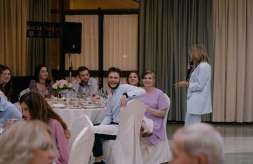 A lively wedding reception with guests enjoying food and conversation indoors.